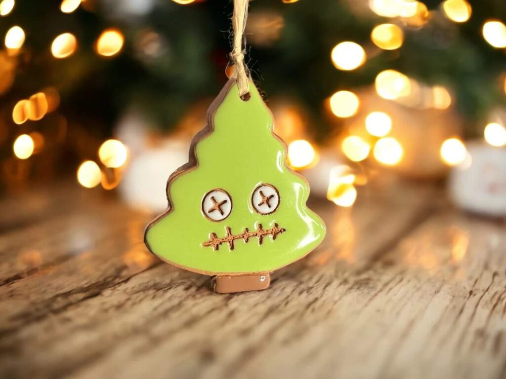 A Christmas tree ornament in the shape of a small Christmas tree with a zombie face and bright green glaze finish